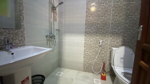 A bathroom with a sink, shower, toilet, and patterned tiles.
