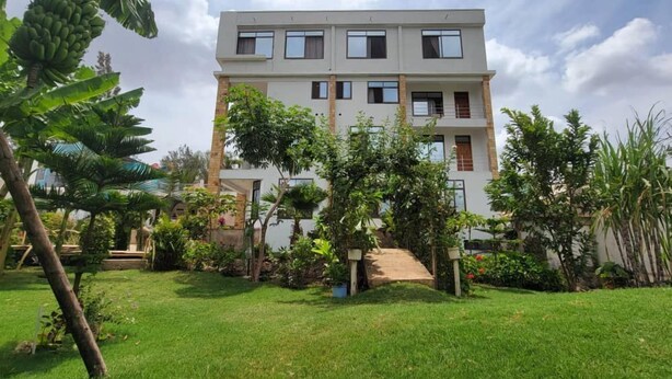 A multi-story building with a flat roof, surrounded by lush greenery and a well-maintained lawn.