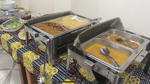 A buffet table with various food items in metal serving trays.