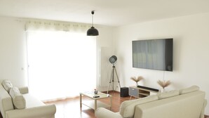 Una sala de estar moderna con un sofá, una mesa de centro y un televisor de pantalla plana montado en la pared.