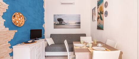 Ett kompakt bostadsutrymme med en matplats, en soffa och en TV.