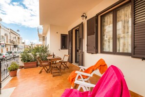 A balcony with a table, chairs, and potted plants.