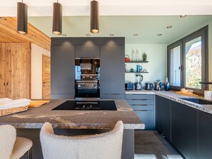 Une cuisine moderne dotée d’un îlot central, d’un four encastré et d’une fenêtre offrant une belle vue.