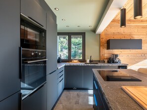 Una cocina moderna con horno empotrado, una isla grande y una pared de acento de madera.