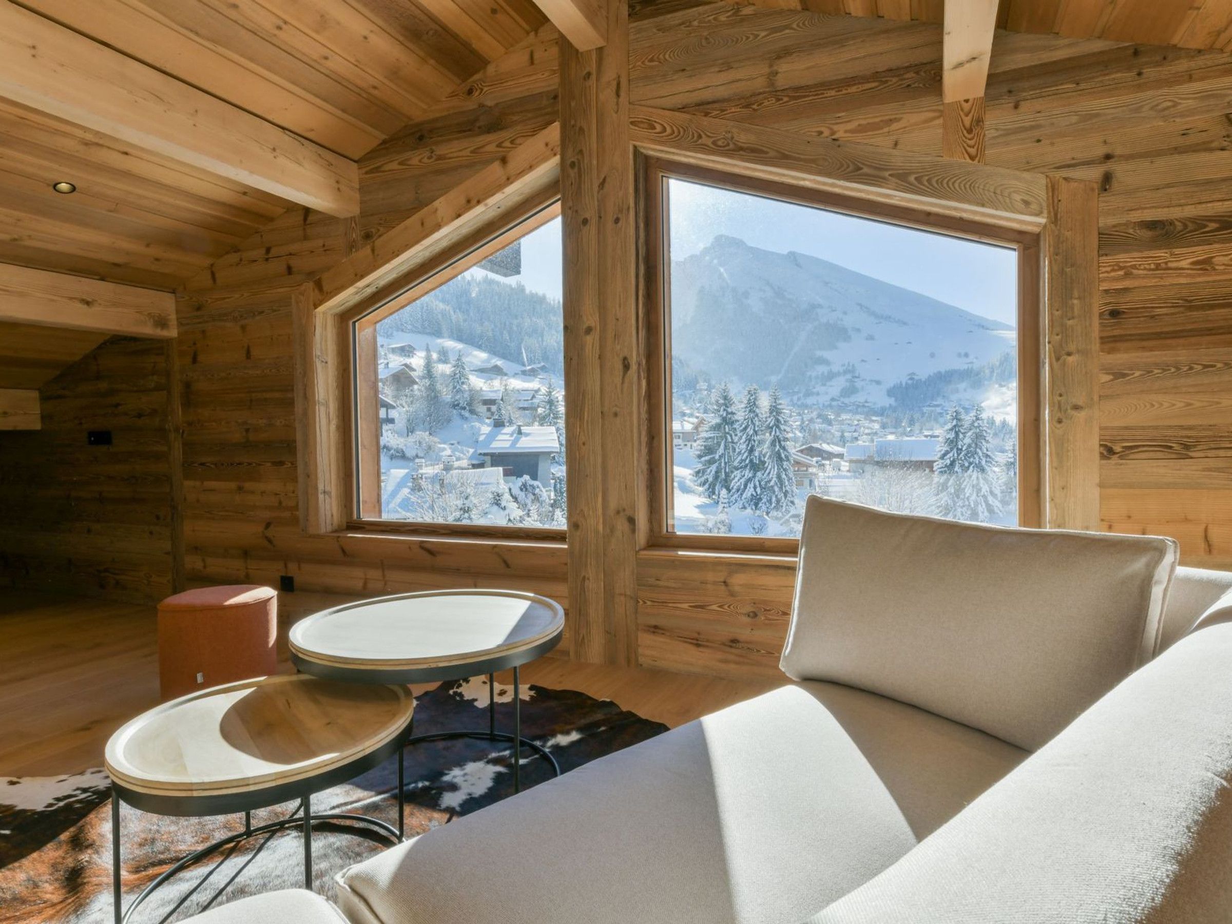 A cozy cabin interior with a large window offering a snowy mountain view.