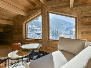 A cozy cabin interior with a large window offering a snowy mountain view.