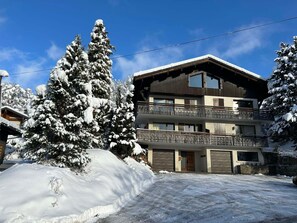 A multi-story building with a balcony, surrounded by snow-covered trees.