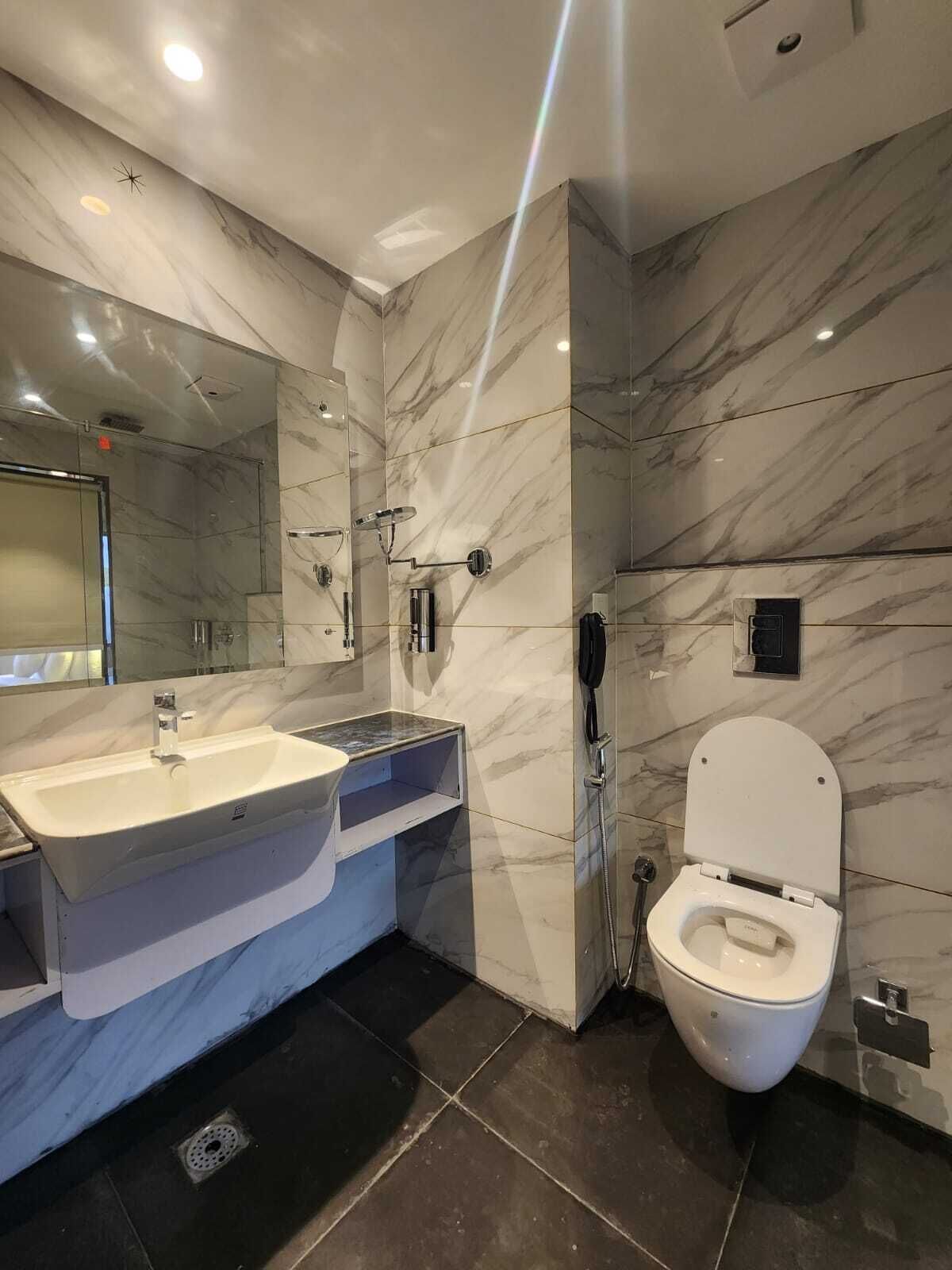 A modern bathroom with a marble vanity, a toilet, and a shower area.