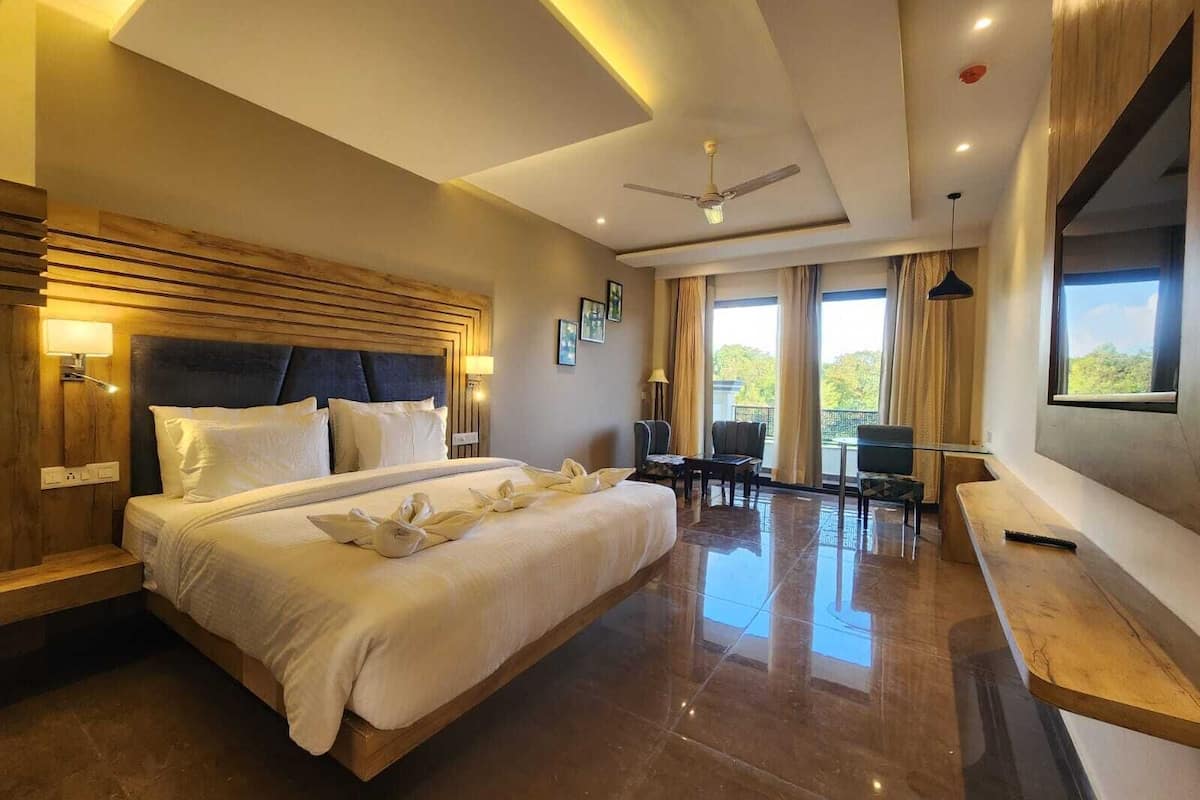 A modern hotel room with a large bed, a ceiling fan, and a seating area with a view of the outdoors.
