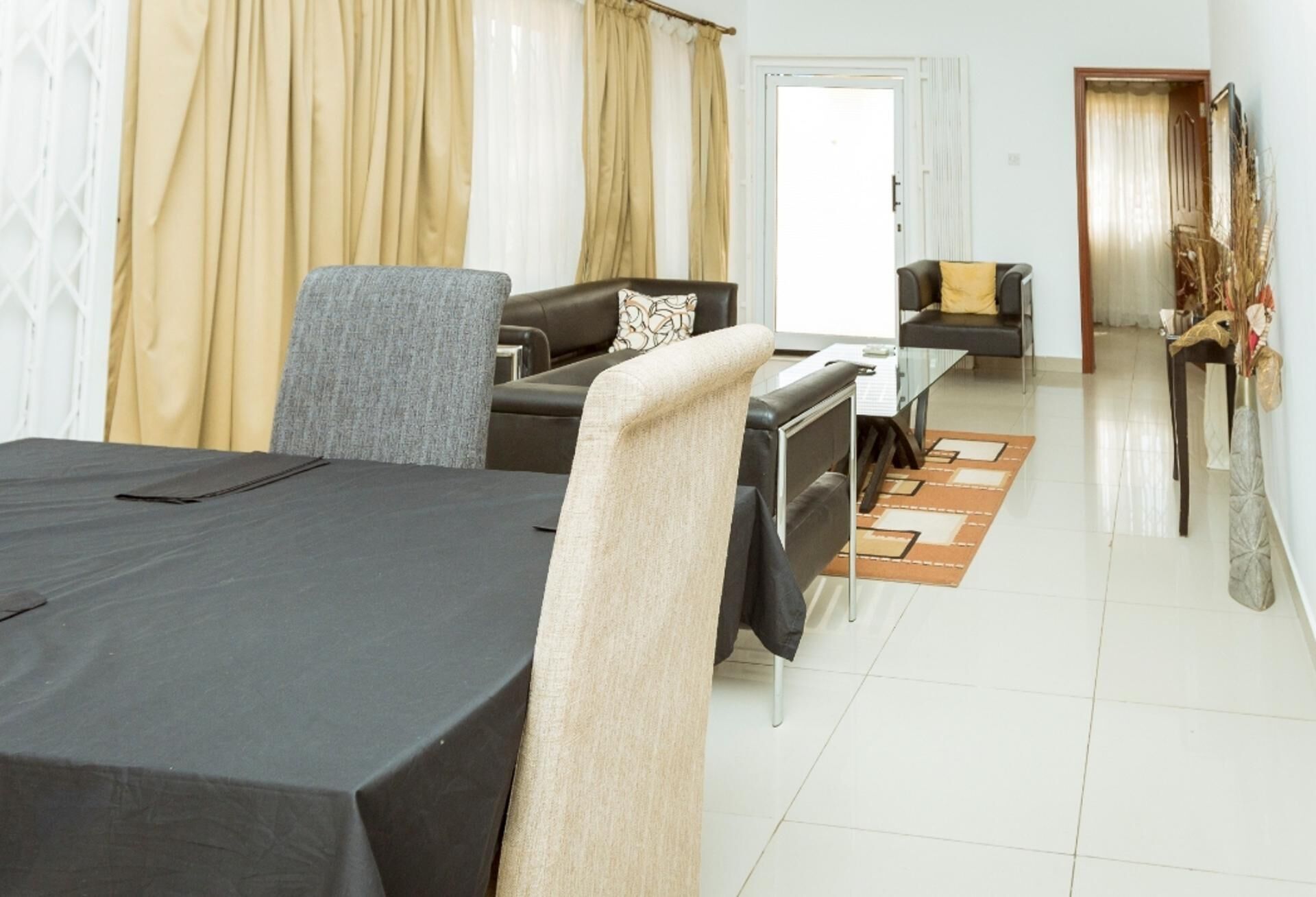 A modern hotel room with a dining area, a sofa, a chair, and a bed.