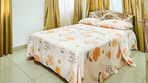 Een slaapkamer met een bed, gordijnen en een bloemenbedekking.