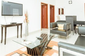 Ein modernes Wohnzimmer mit Glastisch, Ledersofa und flachbildschirm-Fernseher an der Wand.