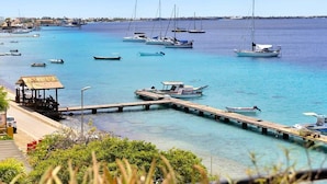 Un puerto deportivo con varias embarcaciones amarradas, un muelle de madera y una pequeña estructura con techo.
