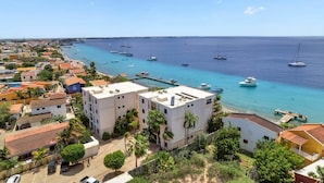 Un pueblo costero con edificios a lo largo del frente marítimo, barcos en el agua y un cielo despejado.