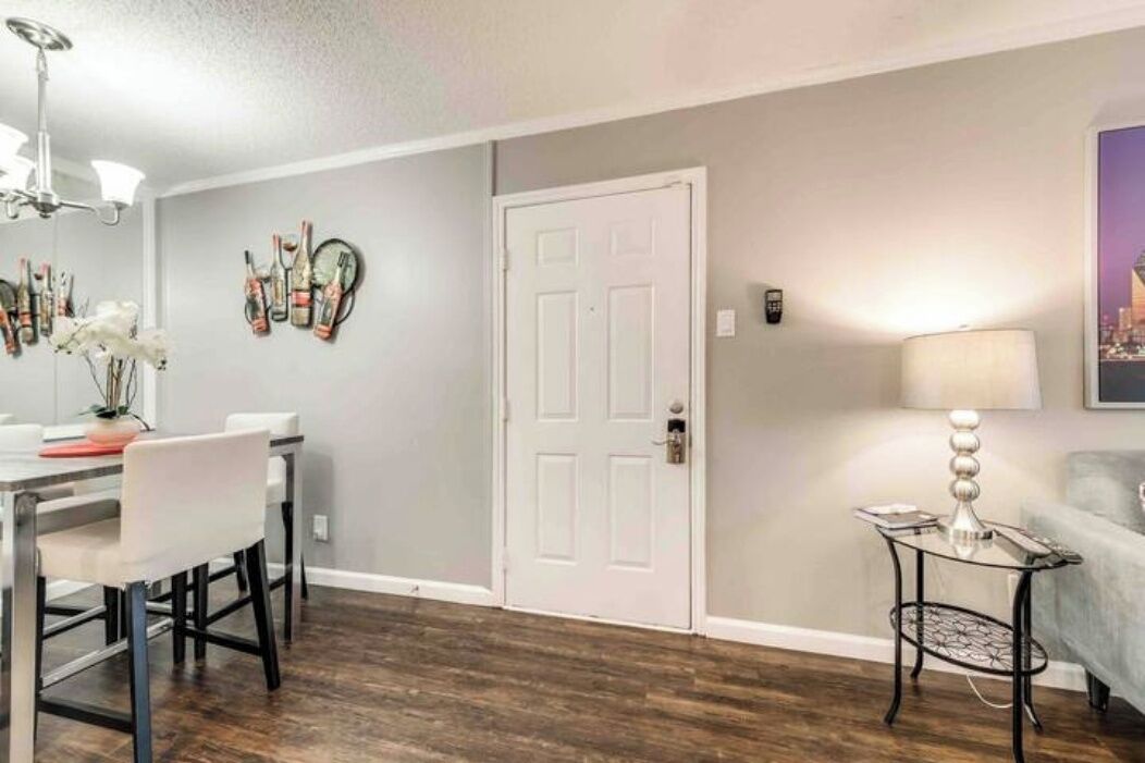 A dining area with a table and chairs, a white door, and a lamp on a side table.