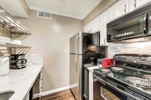A modern kitchen with stainless steel appliances, white cabinetry, and a built-in oven. - I36 - Apt|Yard|11mi to Fair Park|Sleeps 4 (Irving)