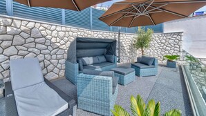 An outdoor seating area with wicker furniture and stone walls.