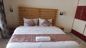 A neatly made bed with a wooden headboard, two pillows, and a patterned bedspread. - Him Hilton Luxury Hotel (Krishangarh)
