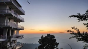 A multi-story building with balconies, overlooking a mountainous landscape during sunset. - Him Hilton Luxury Hotel (Krishangarh)