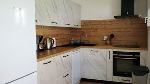 Une cuisine moderne avec des meubles de couleur blanche en marbre, un plan de travail en bois, un lave-vaisselle Bosch, un four Siemens et une hotte noire.