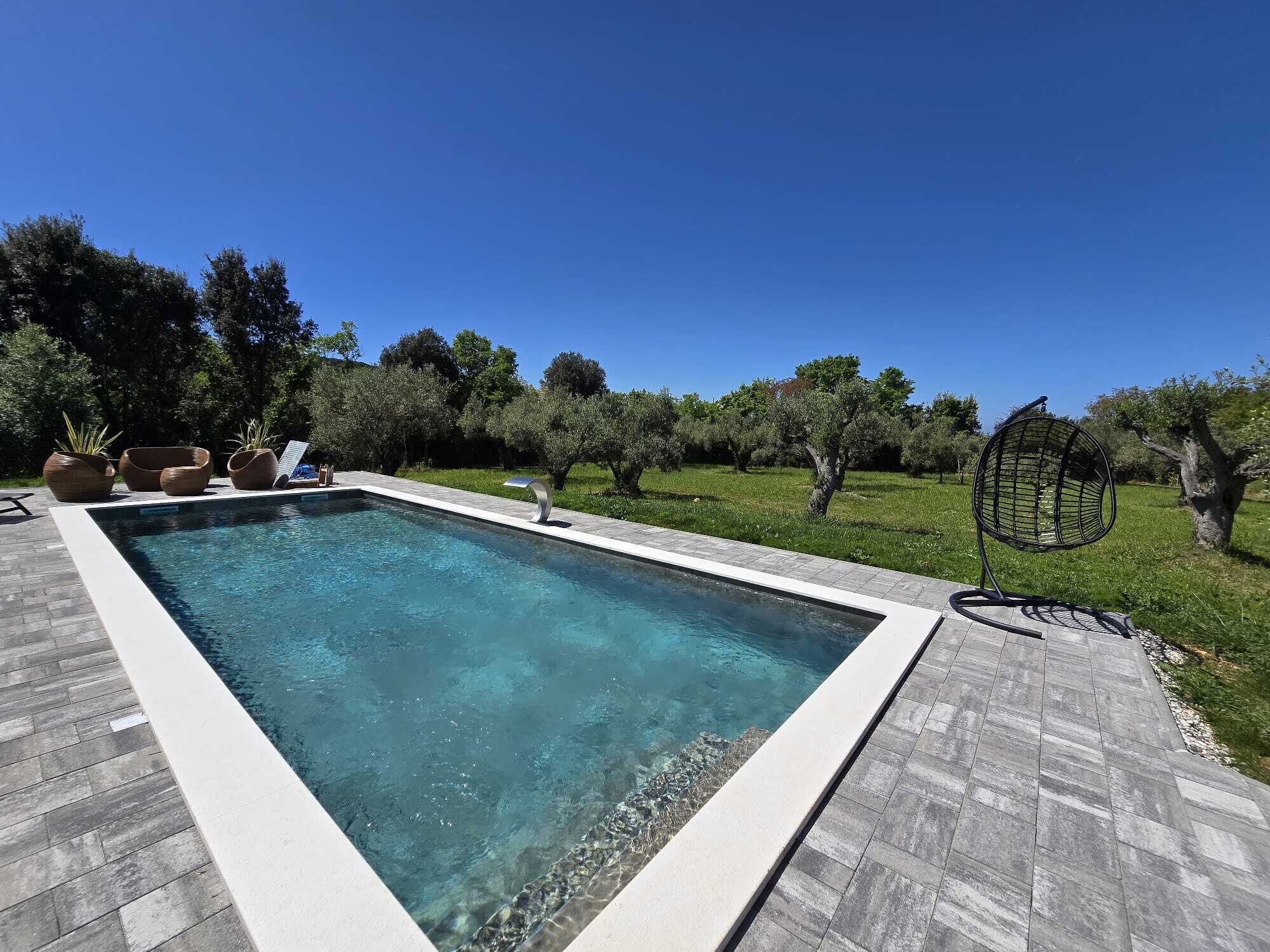 A rectangular swimming pool with clear water, surrounded by a tiled deck.