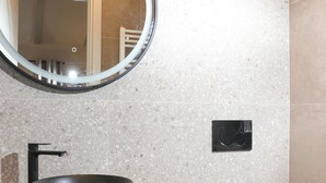 A modern bathroom with a round mirror, a black sink, and a white toilet. - Olive Garden Paradise with Swimming pool (Rovinj)