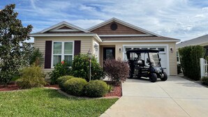 Una casa de dos pisos con garaje, entrada para coches y césped bien cuidado.