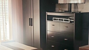 A bedroom with a bed, a wardrobe, a television, and a waste bin. - Altamonte Luxury Studio: Shops, Parks (Altamonte Springs)
