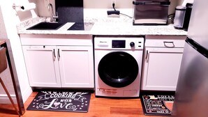 A compact kitchen with a dishwasher, washing machine, and a coffee maker. - Altamonte Luxury Studio: Shops, Parks (Altamonte Springs)