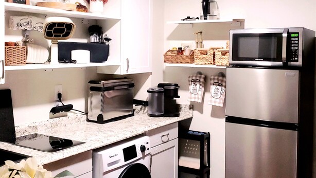A kitchen with white cabinets, a microwave, a coffee maker, and a washing machine. - Altamonte Luxury Studio: Shops, Parks (Altamonte Springs)