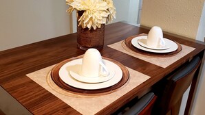 A dining table with two white ceramic cups on matching saucers, a decorative vase with flowers, and a textured brown table runner. - Altamonte Luxury Studio: Shops, Parks (Altamonte Springs)