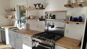 Eine moderne Küche mit Edelstahlherd, Holz Arbeitsplatten und eingebauten Schränken.