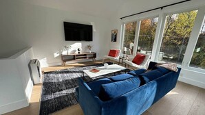 Ein modernes Wohnzimmer mit einem blauen Sofa, einem Couchtisch und einem an der Wand montierten Fernseher.