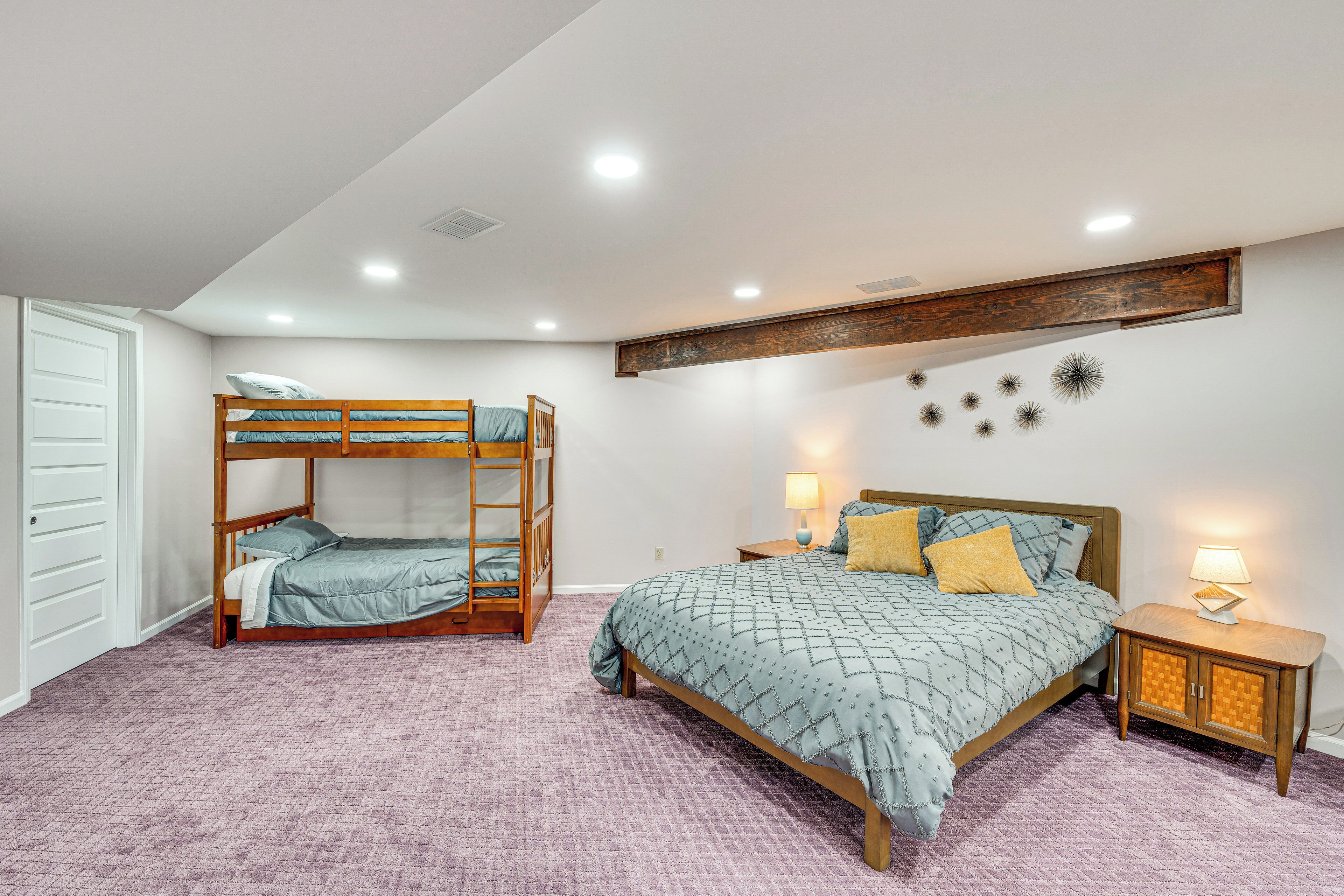 A bedroom with a bunk bed, a single bed, a nightstand, and a wall-mounted shelf.