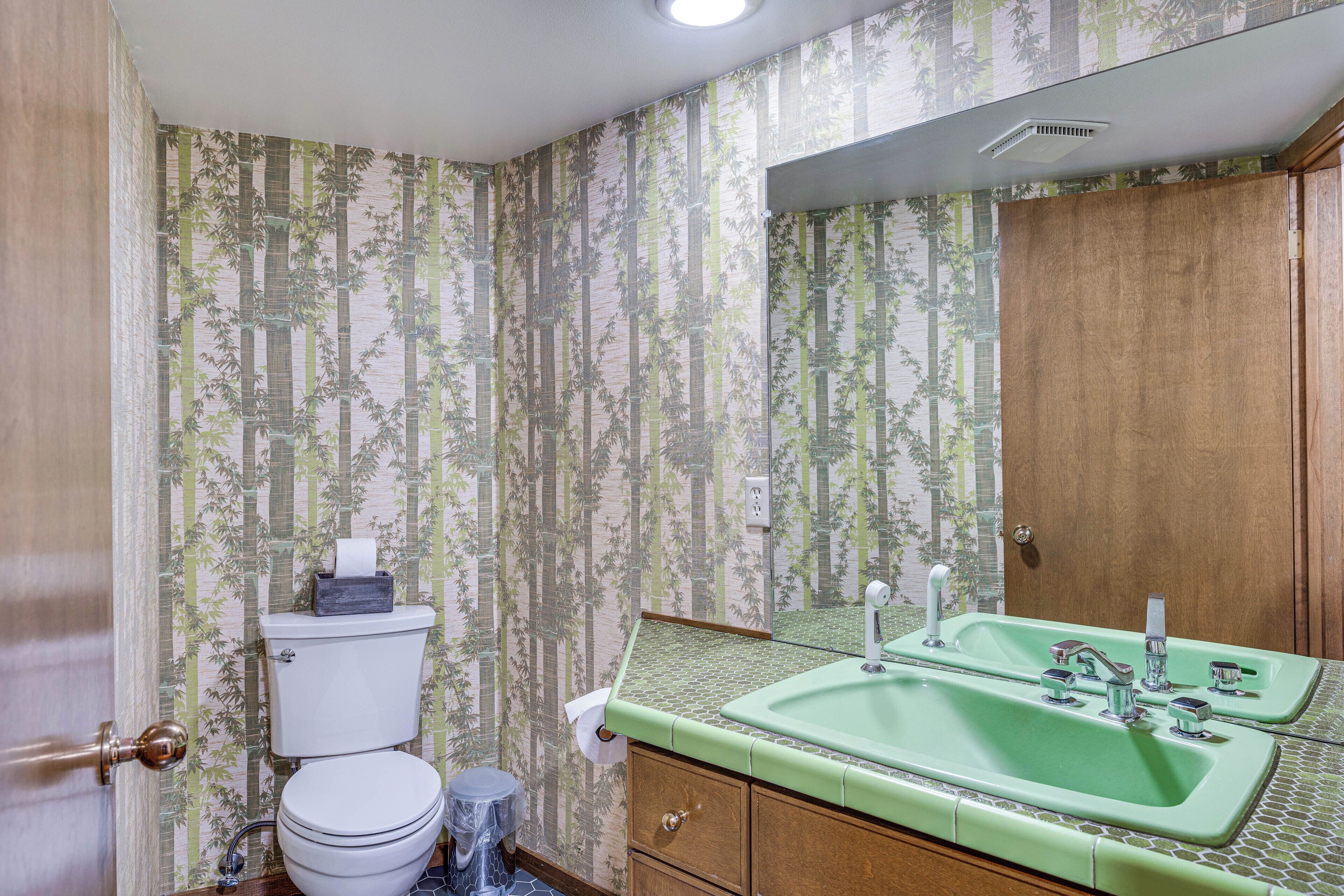 A bathroom with a toilet, sink, and mirror.