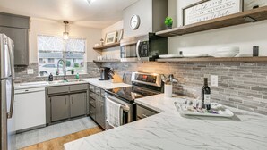 A modern kitchen with stainless steel appliances, a marble countertop, and a brick backsplash. - Updated Duplex Home < 1 Mi to Downtown Enumclaw! (Enumclaw)
