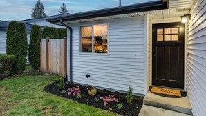 A house with a dark front door, a window with a geometric pattern, and a wooden fence. - Updated Duplex Home < 1 Mi to Downtown Enumclaw! (Enumclaw)