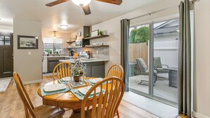 A dining area with a wooden table, chairs, and a ceiling fan. There is a kitchen in the background with a countertop and cabinets. - Updated Duplex Home < 1 Mi to Downtown Enumclaw! (Enumclaw)
