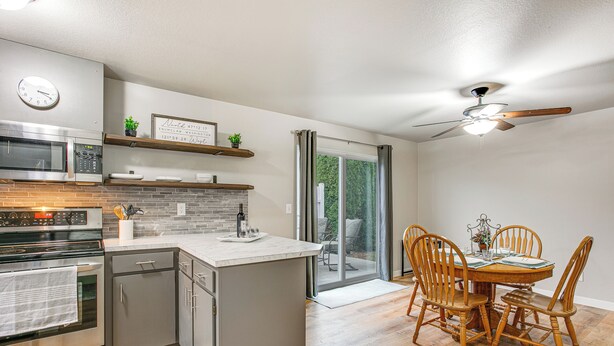 A modern kitchen with a built-in oven, microwave, and dishwasher. There is a dining area with a wooden table and chairs. - Updated Duplex Home < 1 Mi to Downtown Enumclaw! (Enumclaw)