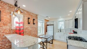 A kitchen with a brick wall, white cabinets, a granite countertop, and a gas stove. - 15 Mi to Amish Village: Cozy Lancaster Apt! (Lancaster)