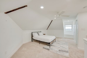 Une chambre à coucher avec un lit, un ventilateur de plafond et une fenêtre.