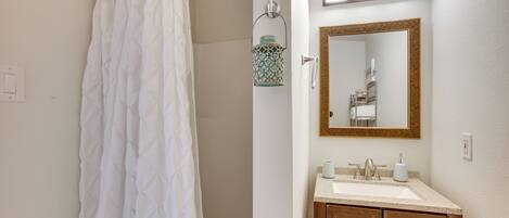 A bathroom with a shower curtain, a sink, a mirror, and a hanging lantern.