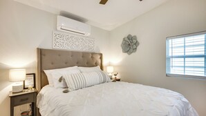 Una camera da letto con un letto grande, un condizionatore d'aria, un elemento decorativo a parete e una finestra con persiane.