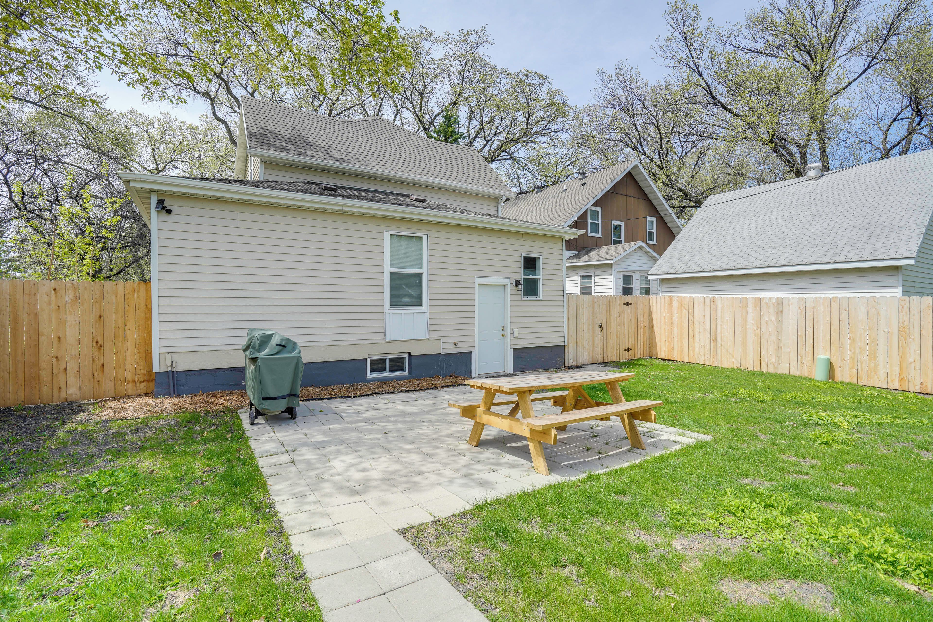 A backyard with a picnic table, a wooden fence, and a house with a garage.