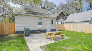 A backyard with a picnic table, a wooden fence, and a house with a garage.