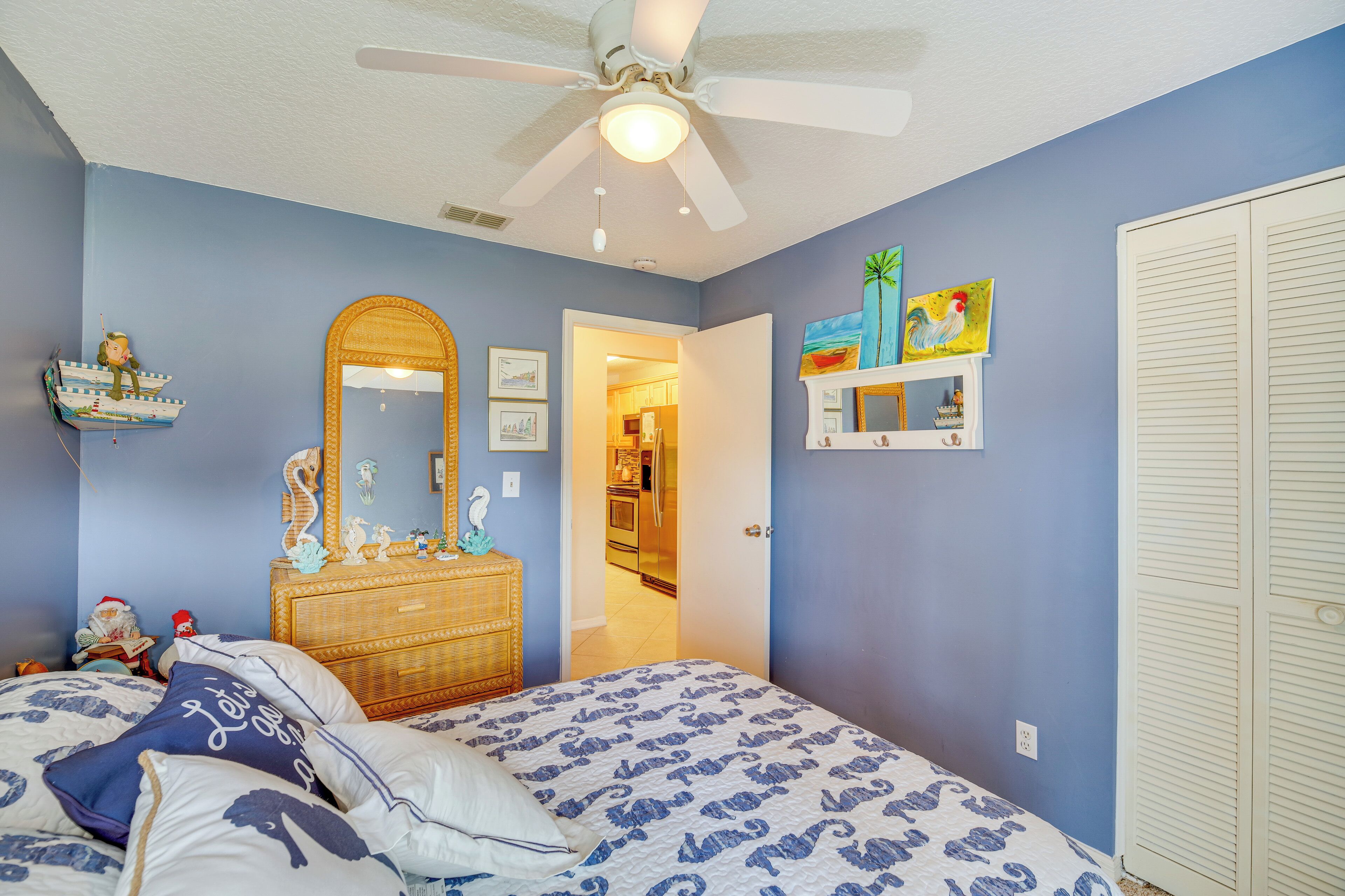 A bedroom with a bed, dresser, and a ceiling fan.