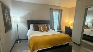 A bedroom with a bed, bedside tables, a ceiling fan, and a window with curtains.