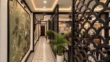 A hallway with a patterned floor, a potted plant, and a decorative wall.