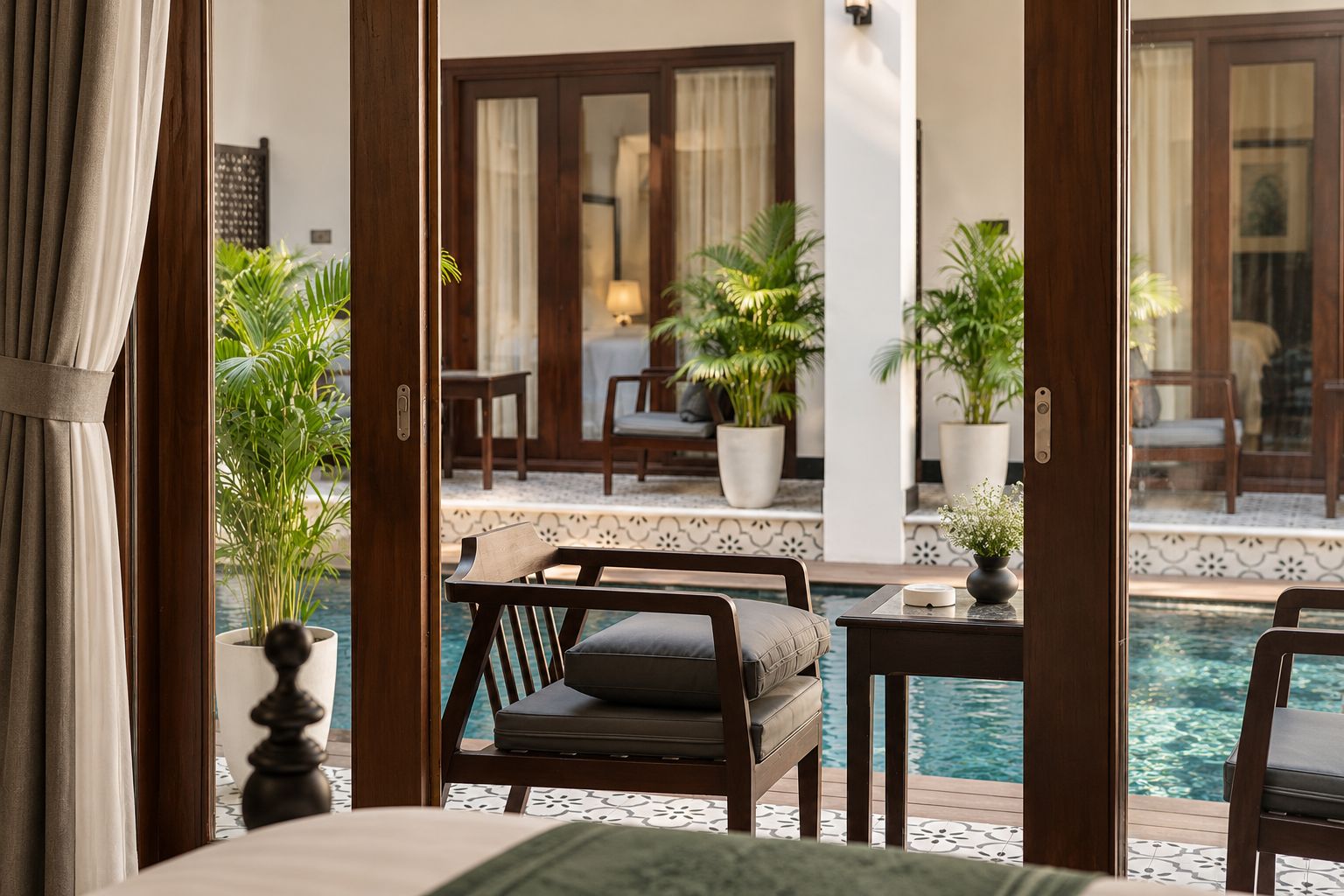 Un espace aménagé au bord de la piscine, avec un canapé, des fauteuils et des plantes en pot.