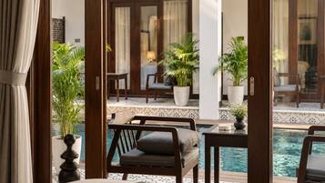 Un espace aménagé au bord de la piscine, avec un canapé, des fauteuils et des plantes en pot.
